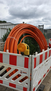 Glasfaserkabel aufgerollt hinter Baustellenbaken zur Sicherheit nach Feirabend des Bautrupp