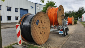 Glasfasrkabeltrommel auf dem Parkstreifen. Eine auf dem Boden, eine auf einem Kabelanhänger