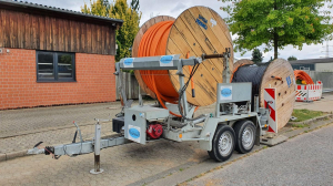 Glasfasrkabeltrommel auf dem Parkstreifen. Eine auf dem Boden, eine auf einem Kabelanhänger